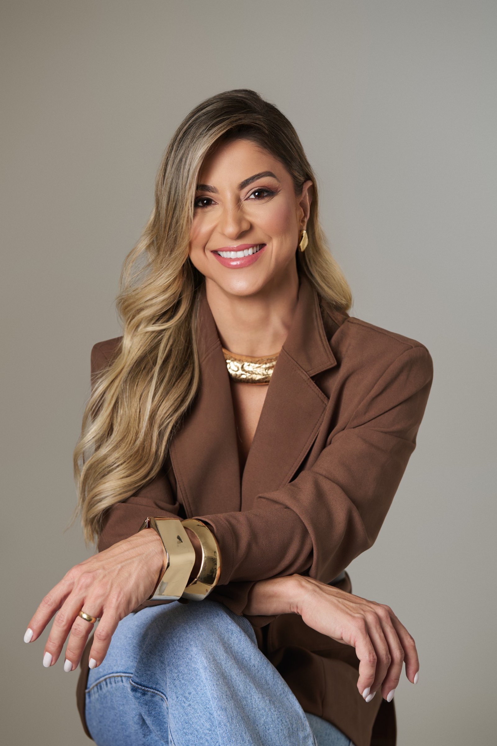 Dra. Francielle Torres sorrindo, de blazer marrom, médica do Instituto Torres em Goiânia